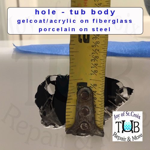 Hole repair in tub body a tape measure is held up to a hole in a fiberglass bathtub. The text and logo informs: Joy of St Croix repairs holes in the tub body of bathtubs made of gelcoat or acrylic on fiberglass or porcelain on steel.